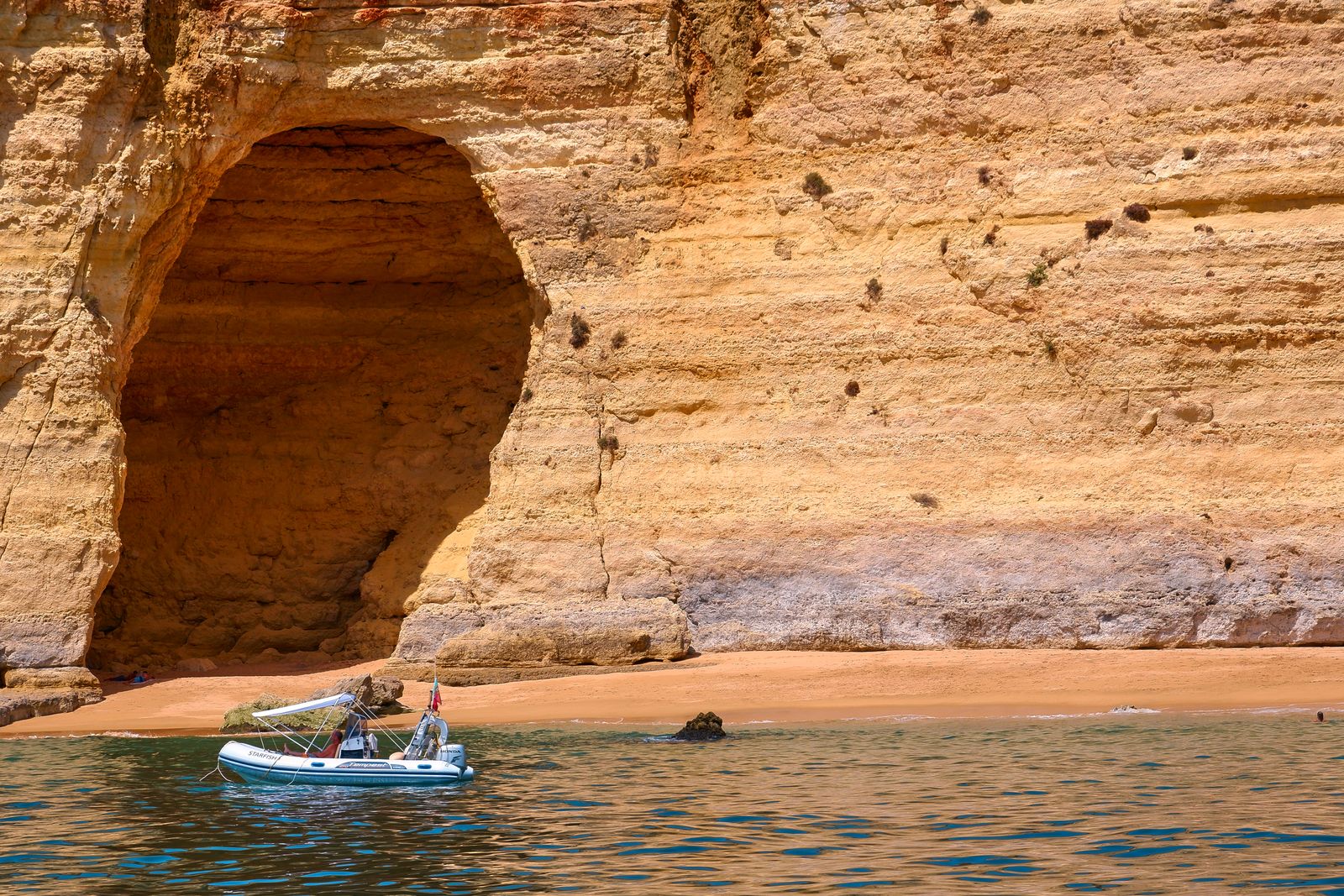 A boat cruising past the Algarve cliffs