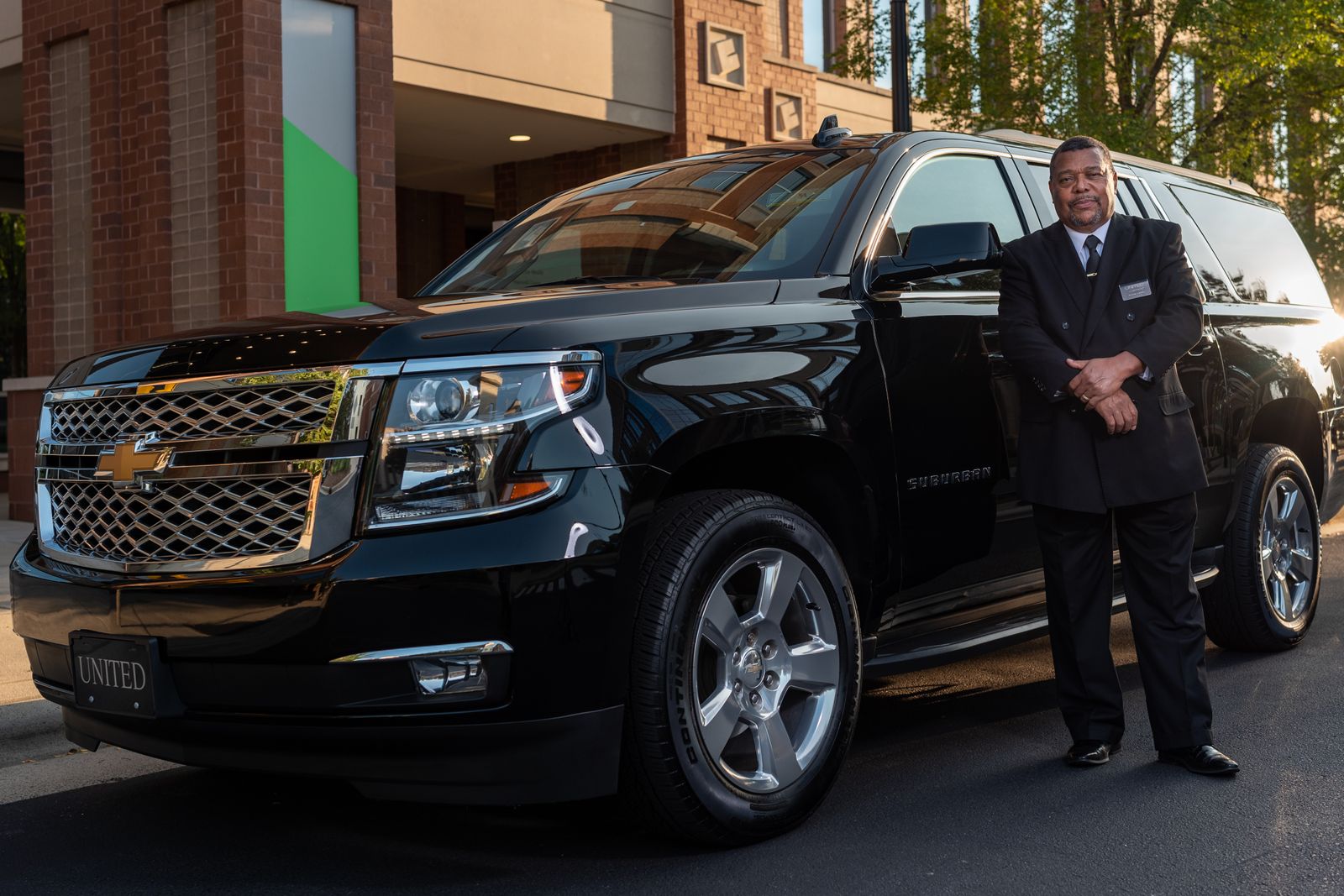 A chauffeur beside a luxury car
